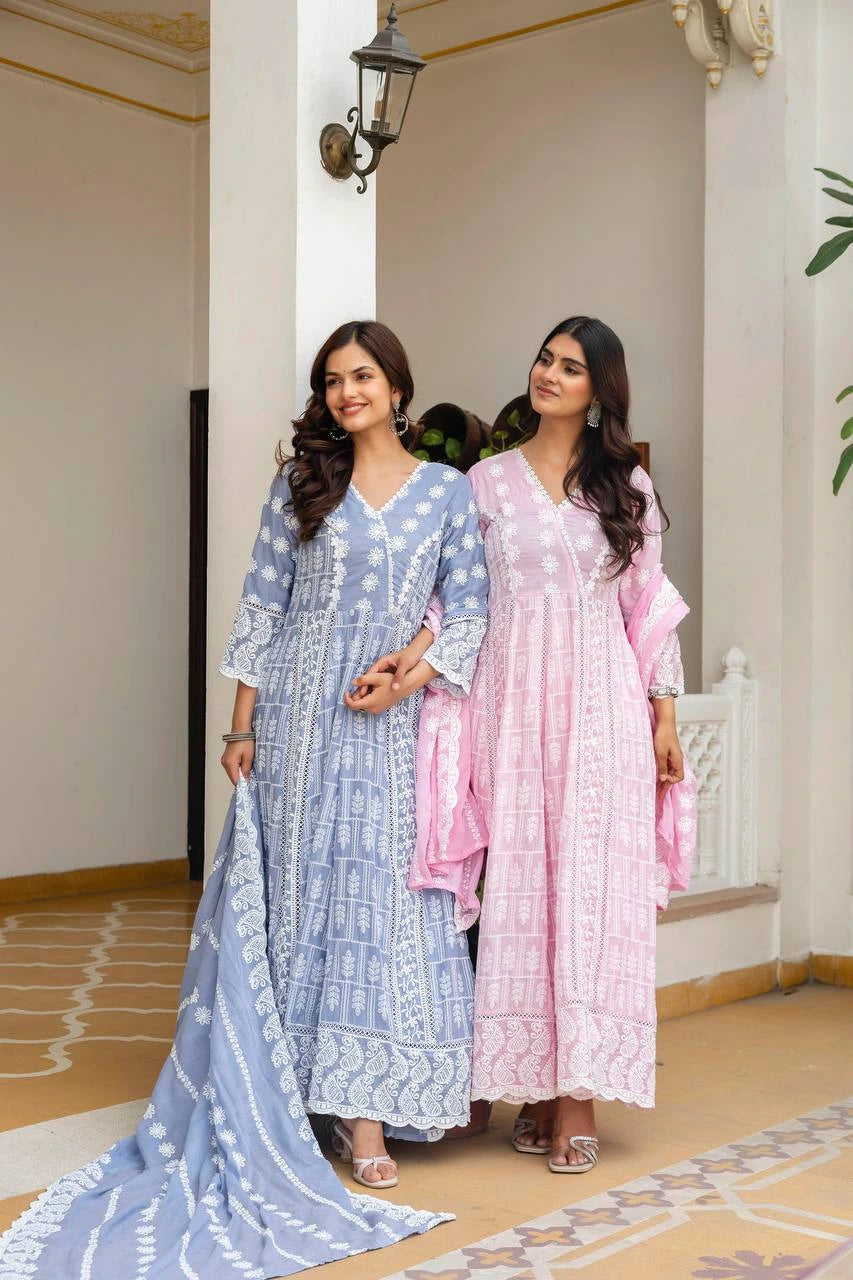 Two women in traditional outfits standing in a decorative indoor setting.