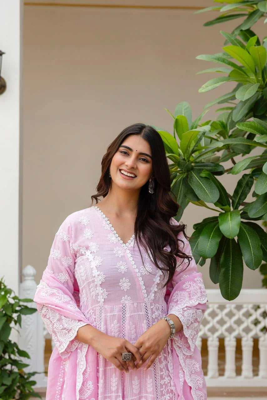 Woman in a pink traditional outfit standing outdoors with greenery around