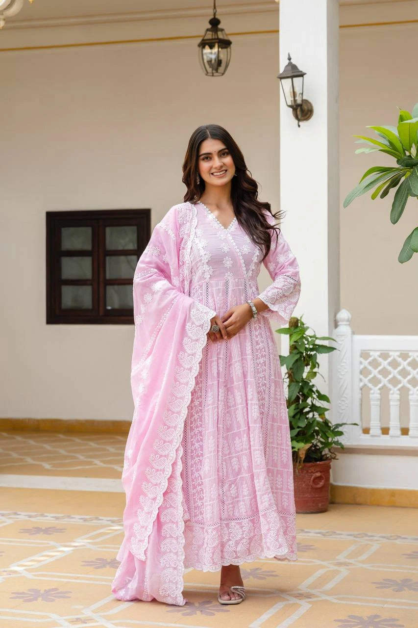 Woman in a pink traditional outfit standing in a decorative indoor setting.