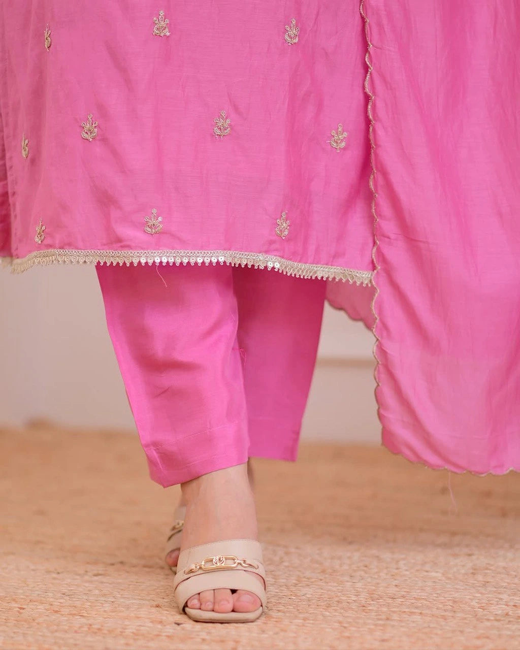 Pink traditional outfit with gold embroidery on a wooden floor