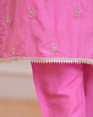 Pink fabric with gold embroidery and a decorative border on a white background