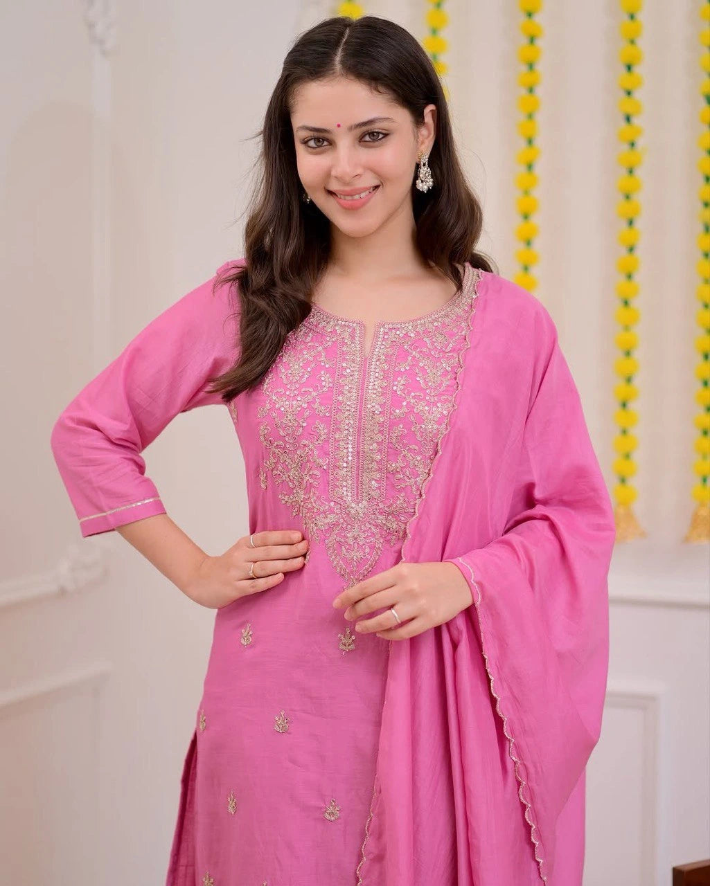 Woman wearing a pink traditional outfit with intricate designs.