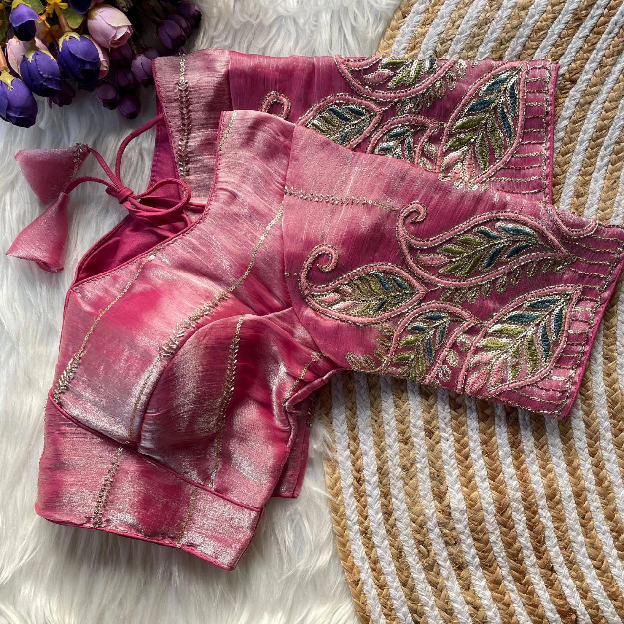 Pink blouse with intricate leaf patterns on a textured surface