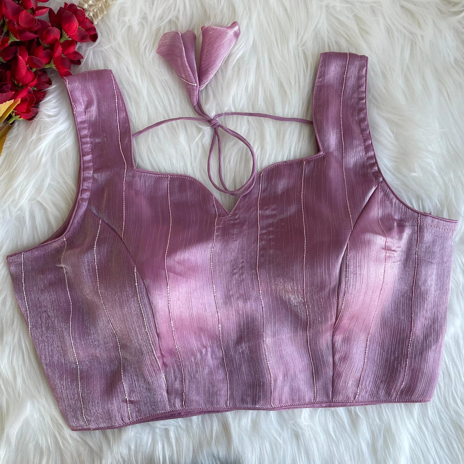 Purple crop top with matching hair accessory on a fluffy white surface with red flowers.