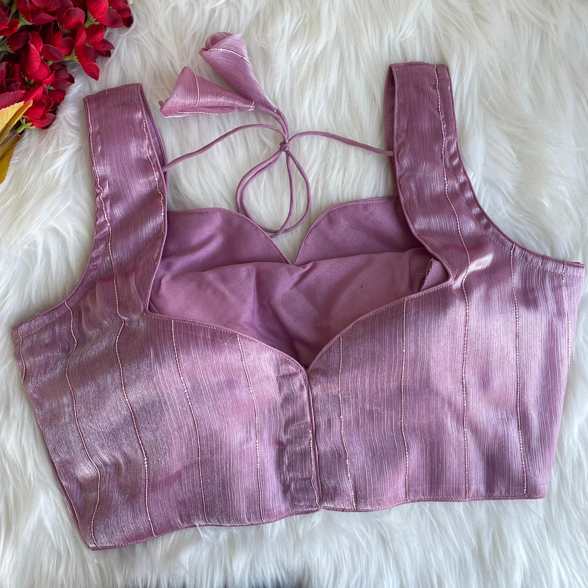 Purple bralette on a white fur surface with red flowers in the corner