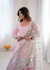 Woman wearing a pink traditional outfit with a white dupatta in a bright room.