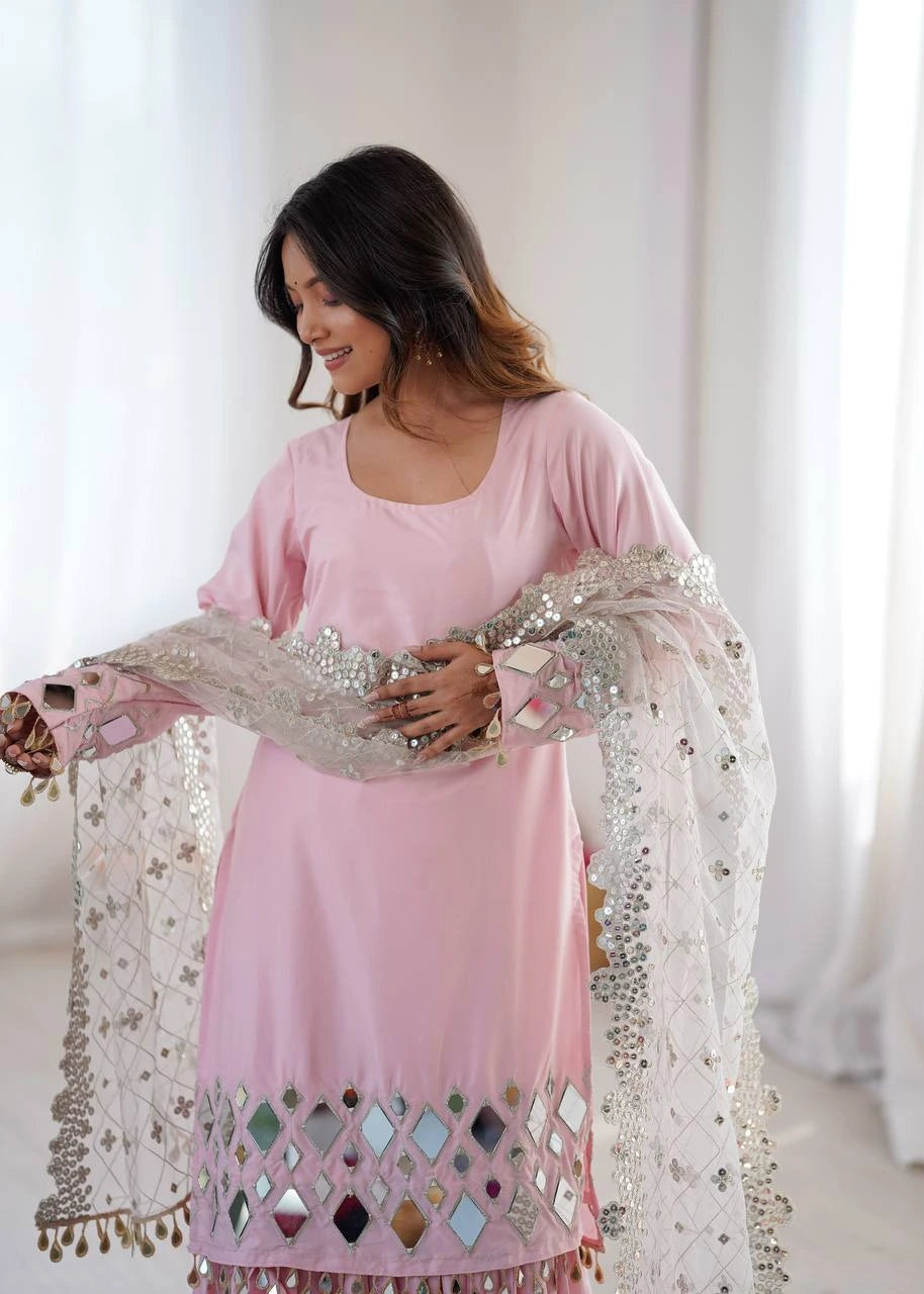 Woman wearing a pink traditional outfit with a sheer dupatta in a bright room.