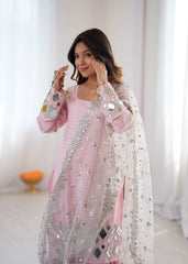 Woman wearing a pink traditional outfit with silver embroidery in a bright room.