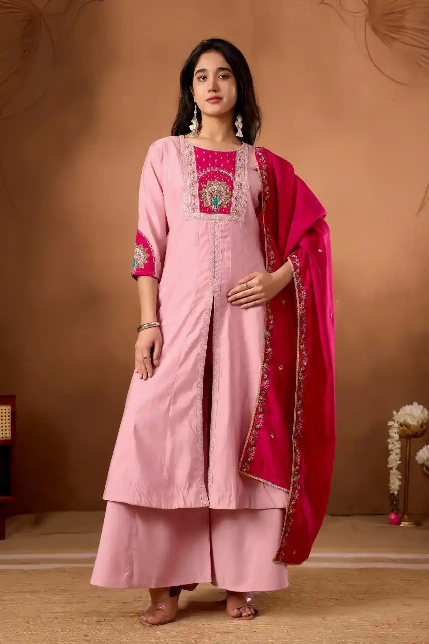 Woman wearing a pink traditional outfit with a red dupatta against a brown background