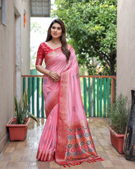 Woman wearing a pink saree with a colorful border outdoors.
