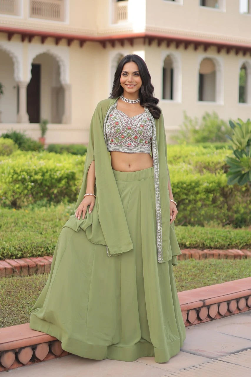 Woman in a green traditional outfit standing outdoors with a building and greenery in the background