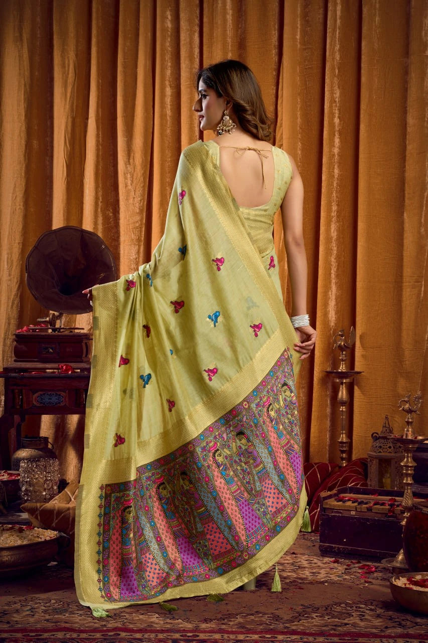 Woman in a traditional yellow saree with colorful patterns in an ornate room.