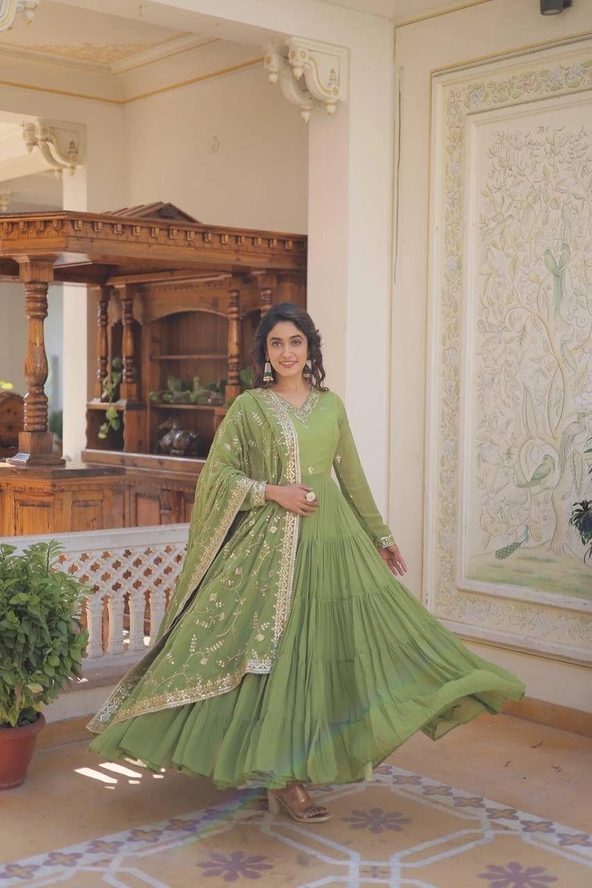 Woman in a green traditional outfit standing in an ornate room.