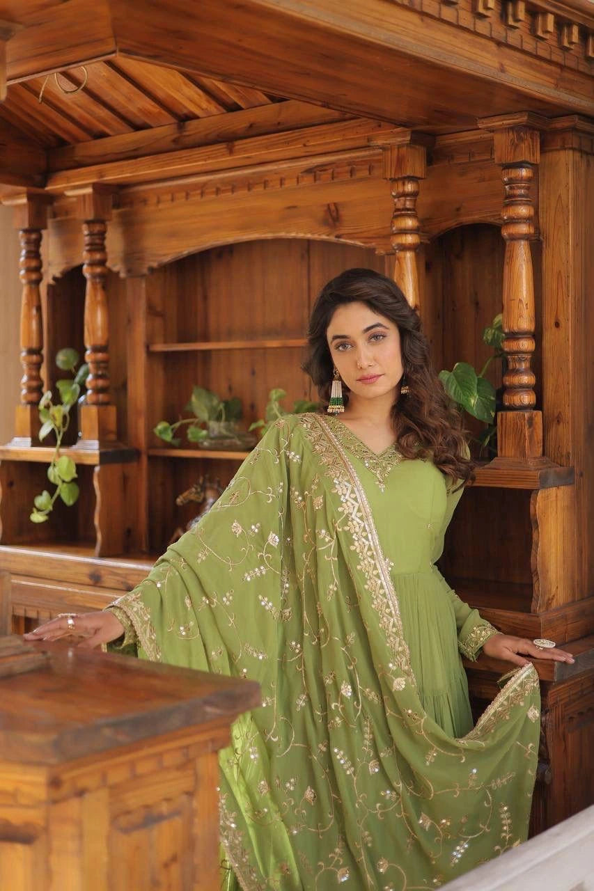Woman in a green traditional outfit standing in front of wooden architectural elements.