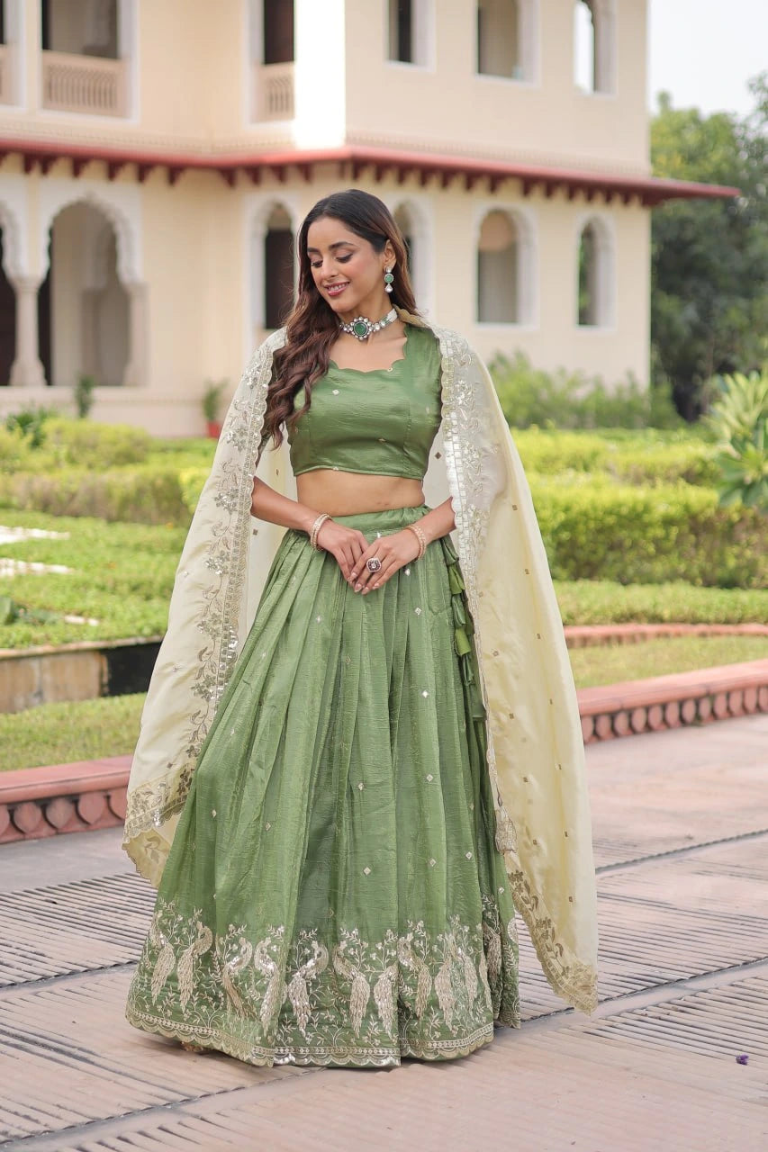Woman in a green traditional outfit with a white dupatta standing in front of a building.