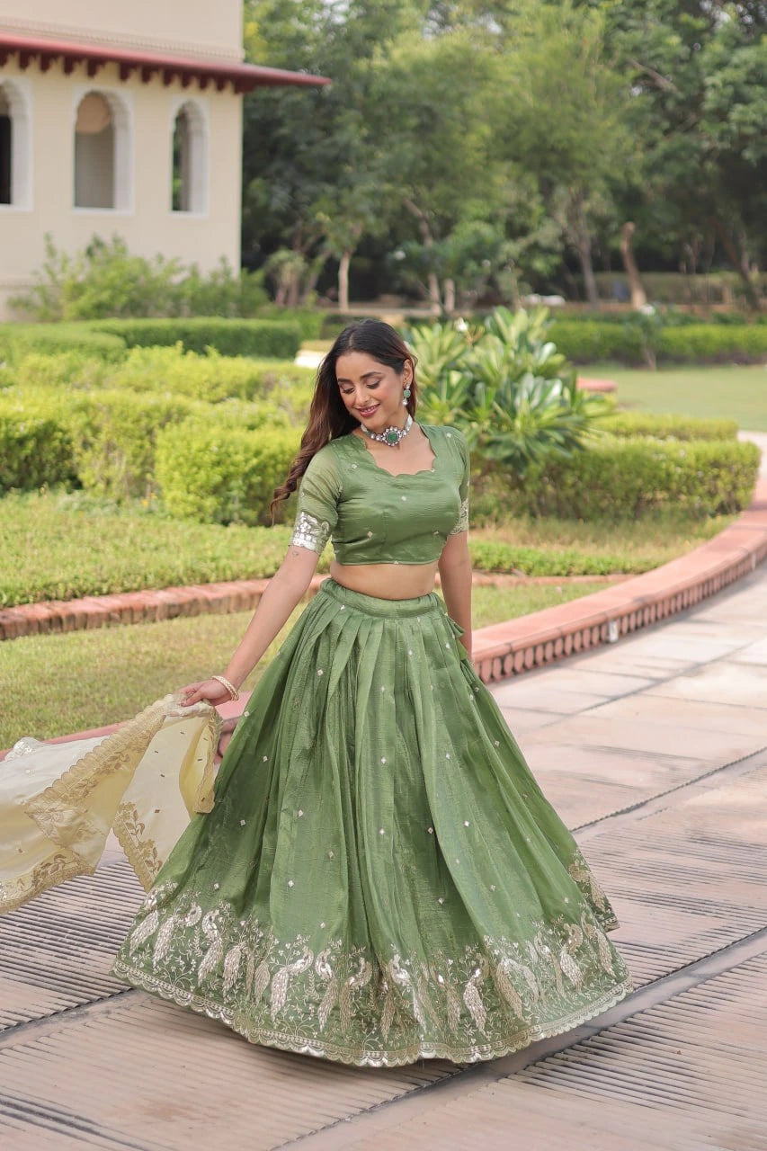 Woman in a green traditional outfit standing on a pathway with greenery in the background