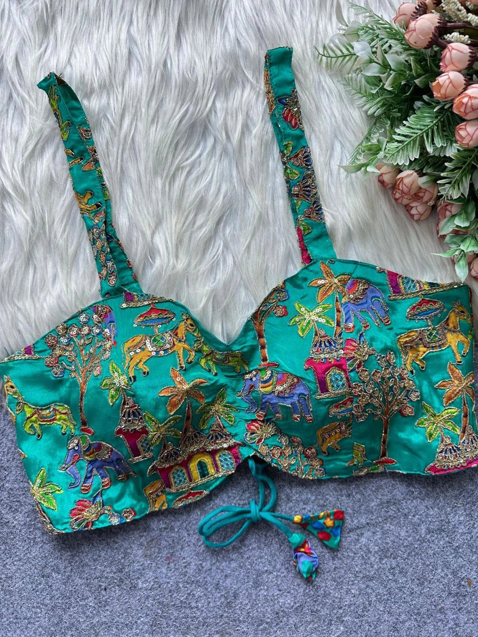 Colorful embroidered top on a textured surface with flowers in the background