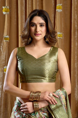 Woman wearing a green traditional outfit with a gold blouse against a brown curtain background