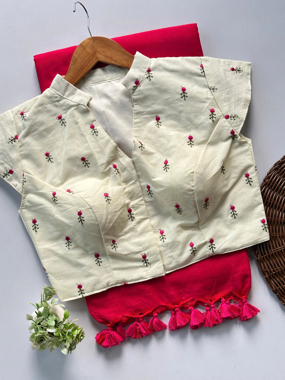 White blouse with floral embroidery and red pants on a white background