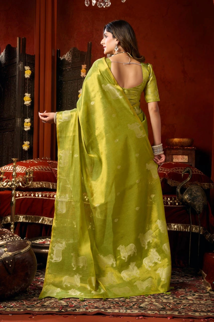 Woman in a green saree standing in a room with decorative elements.