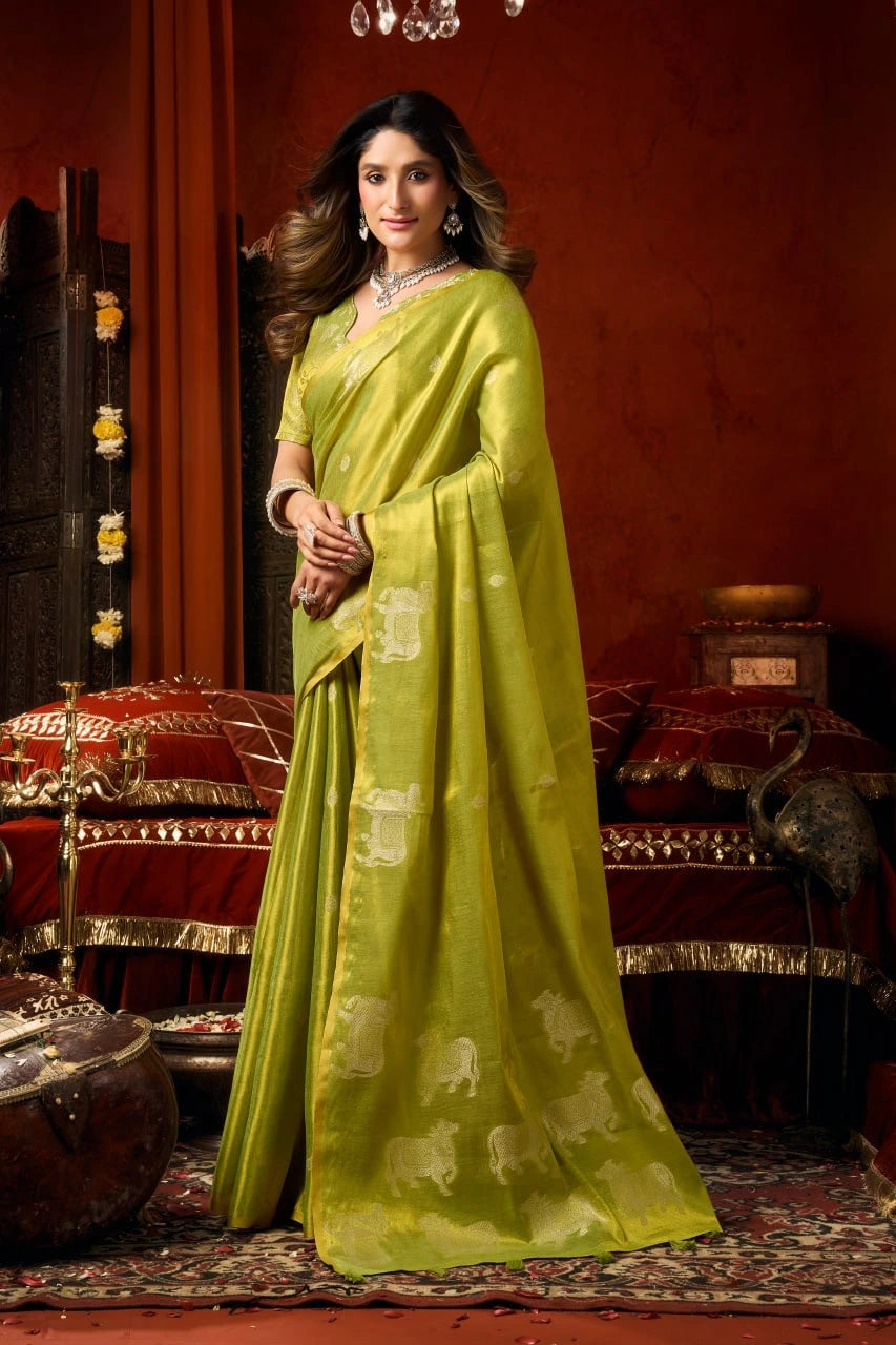 Woman in a green saree with elephant patterns in an ornate room.