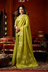 Woman in a green saree with elephant patterns in an ornate room.