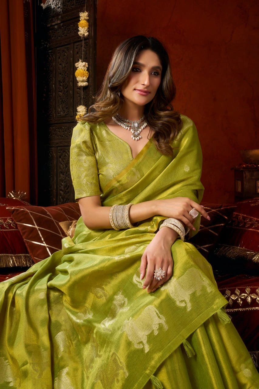 Woman in a green saree sitting on a decorative chair with a red background