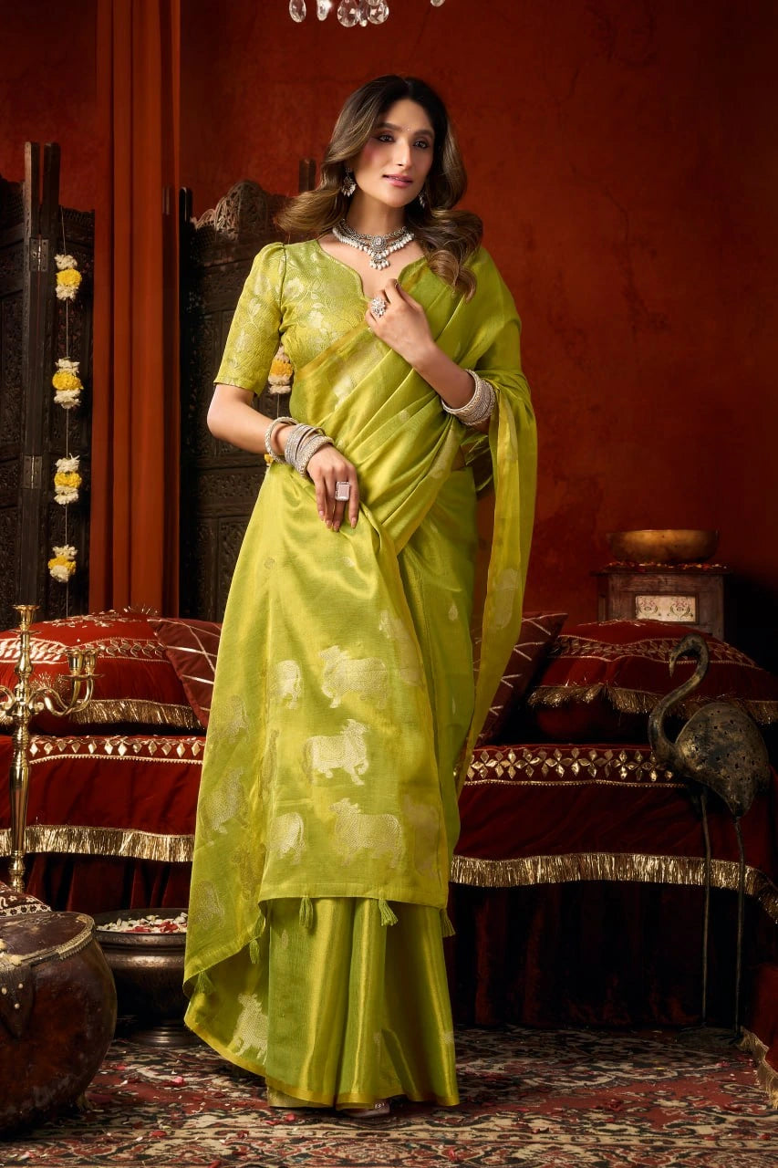 Woman in a green saree posing in a decorated room with red walls and patterned floor.