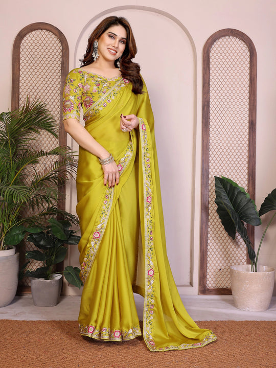 Woman wearing a bright yellow saree with floral patterns indoors.