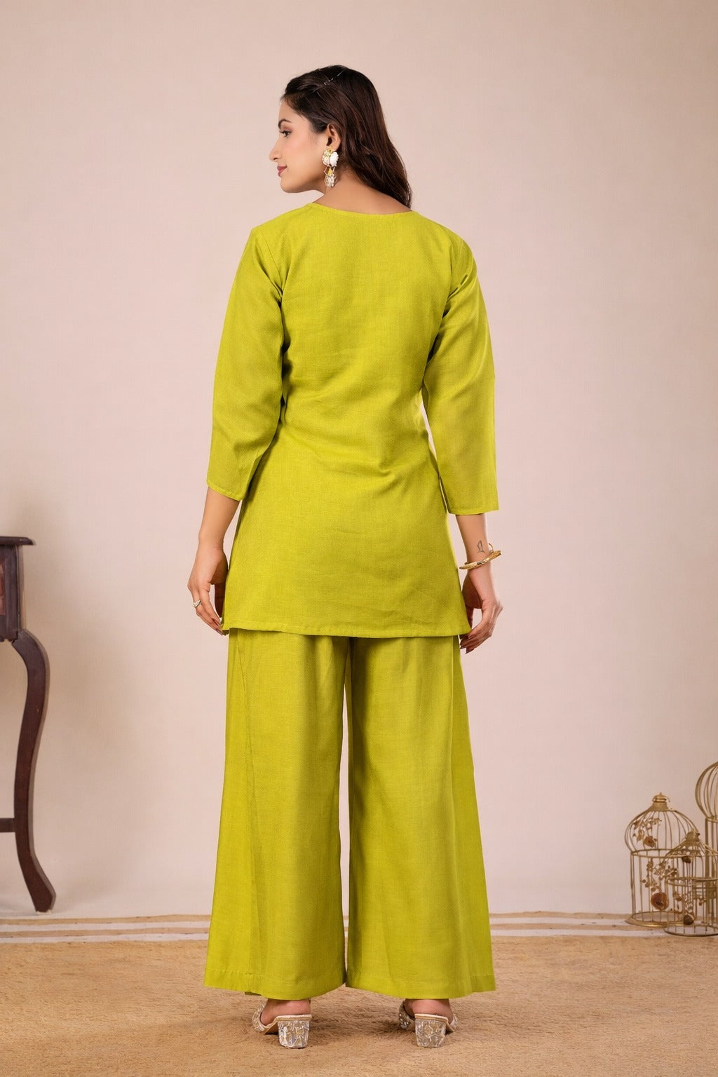Woman wearing a green outfit with wide-leg pants against a beige background