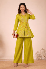Woman wearing a green traditional outfit with a matching handbag against a beige background