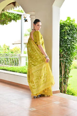 Woman in a yellow saree standing in a garden setting