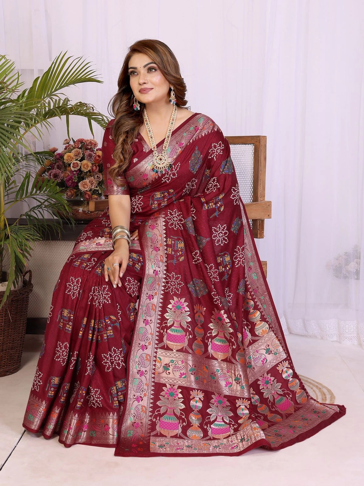 Woman wearing a maroon saree with floral patterns indoors.