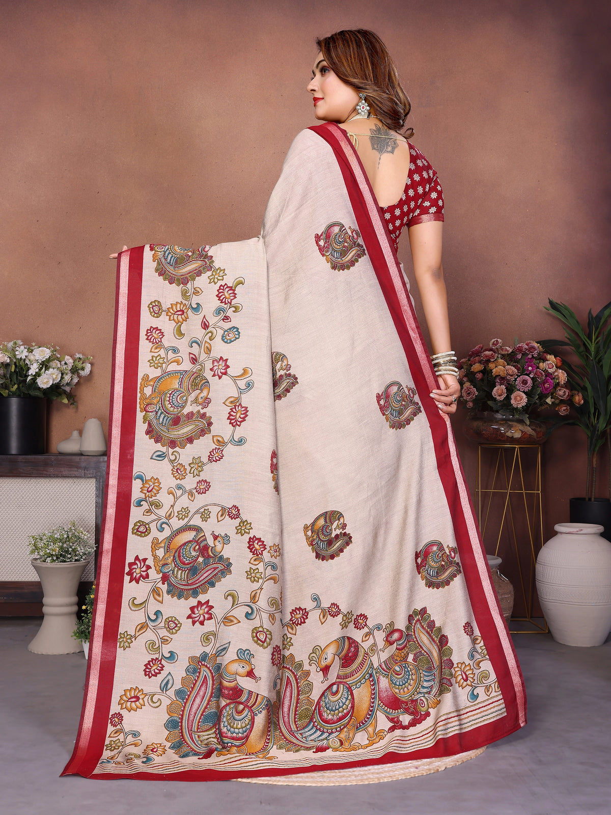 Woman wearing a saree with intricate patterns in a decorated indoor setting