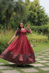 Woman in a red dress standing outdoors on a garden path with greenery.