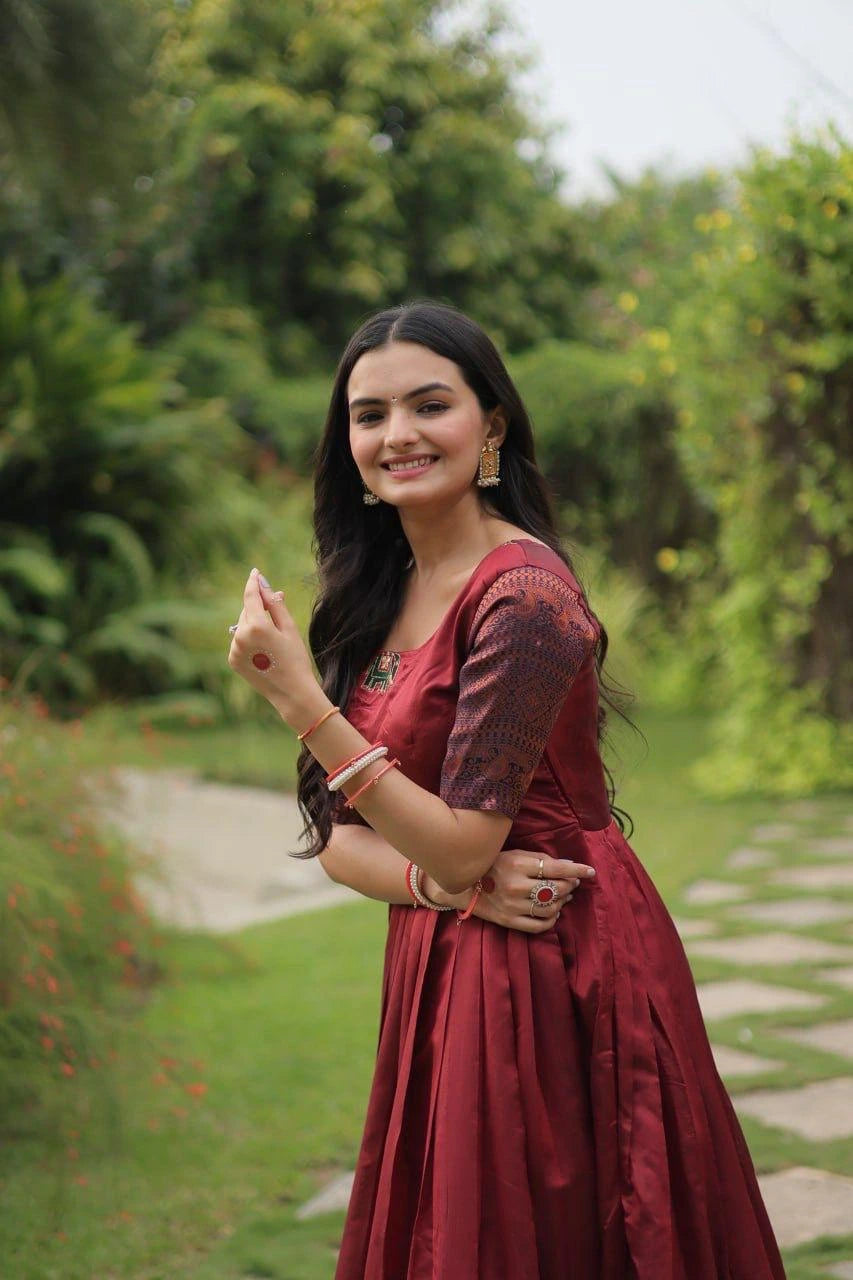 Woman in a red traditional outfit standing outdoors with greenery in the background