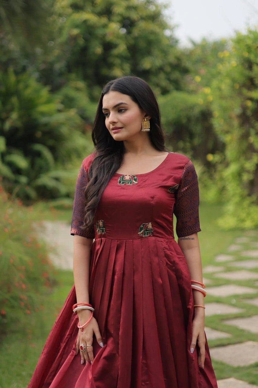 Woman in a red traditional outfit standing outdoors with greenery in the background