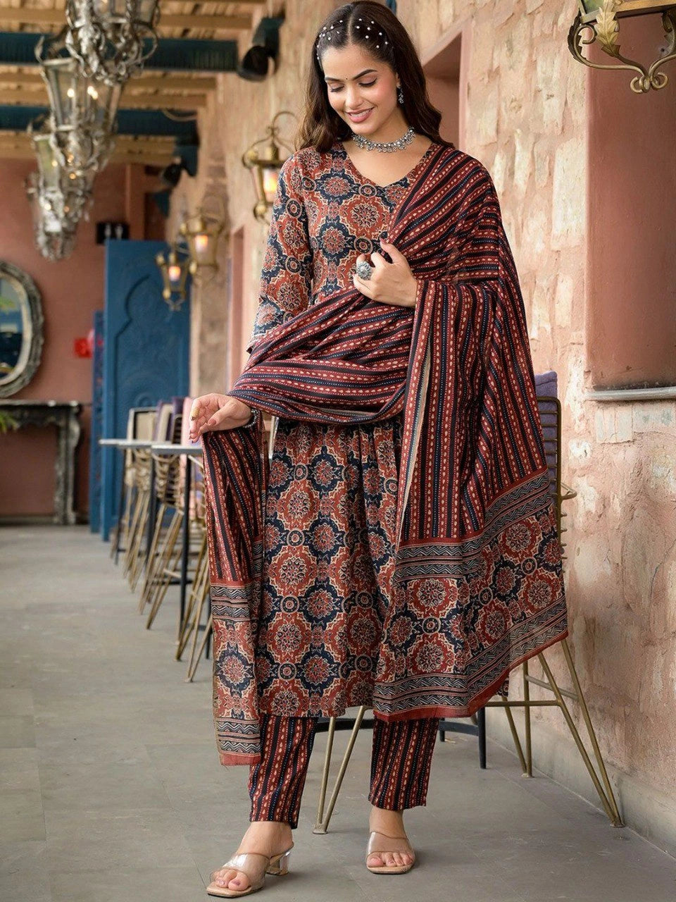 Woman wearing a patterned outfit in an indoor setting with decor elements.
