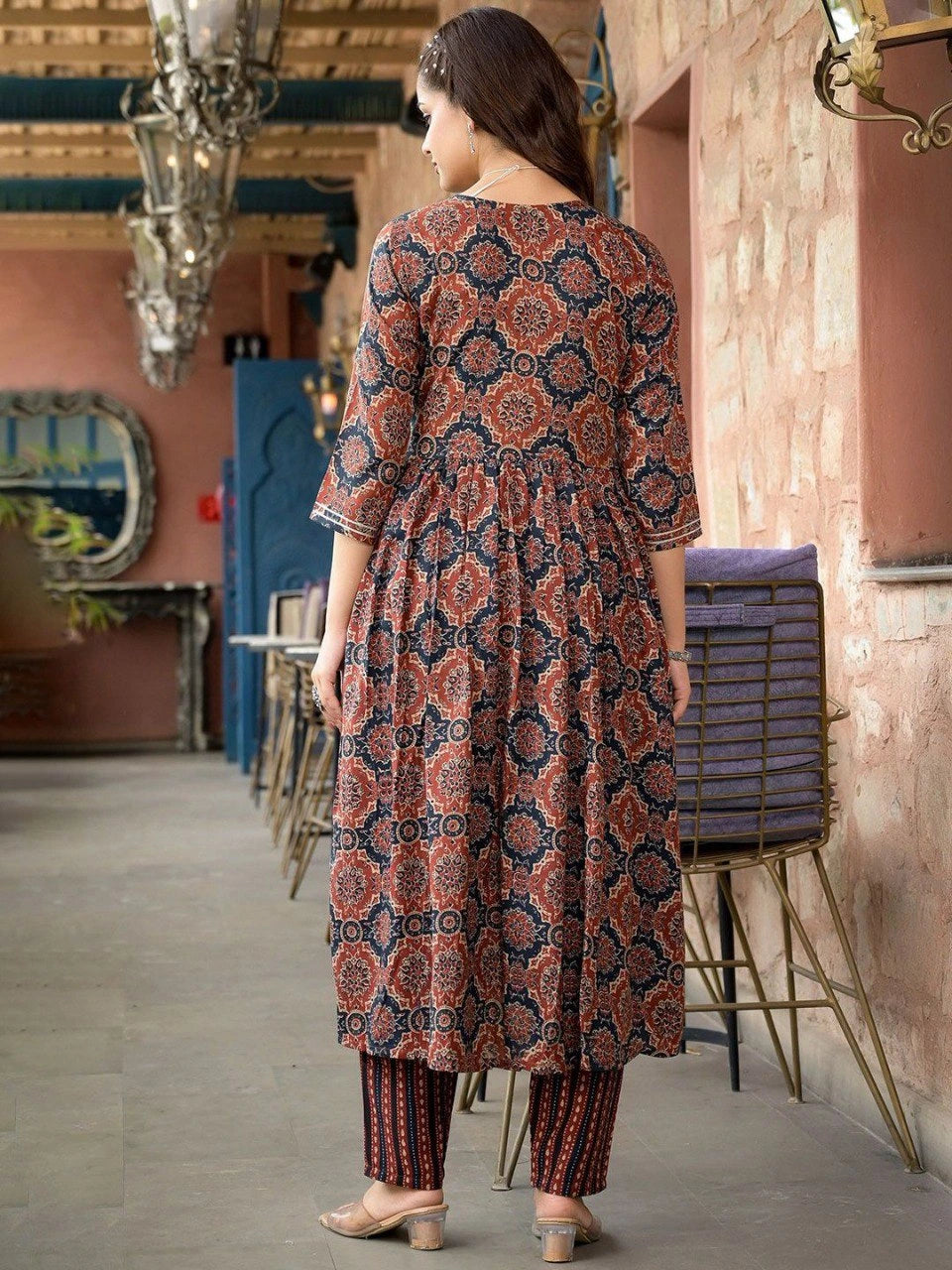 Woman wearing a patterned outfit in an indoor setting with decorative elements.