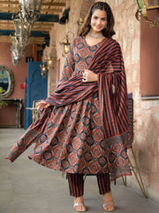 Woman in a traditional patterned outfit standing in an ornate interior setting.