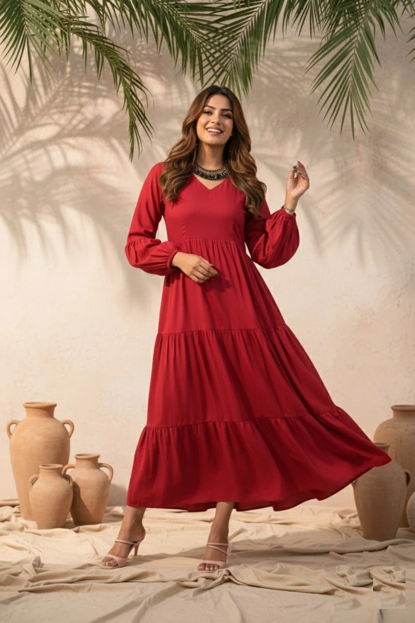 Woman in a red dress standing in front of a neutral background with decorative vases and greenery.
