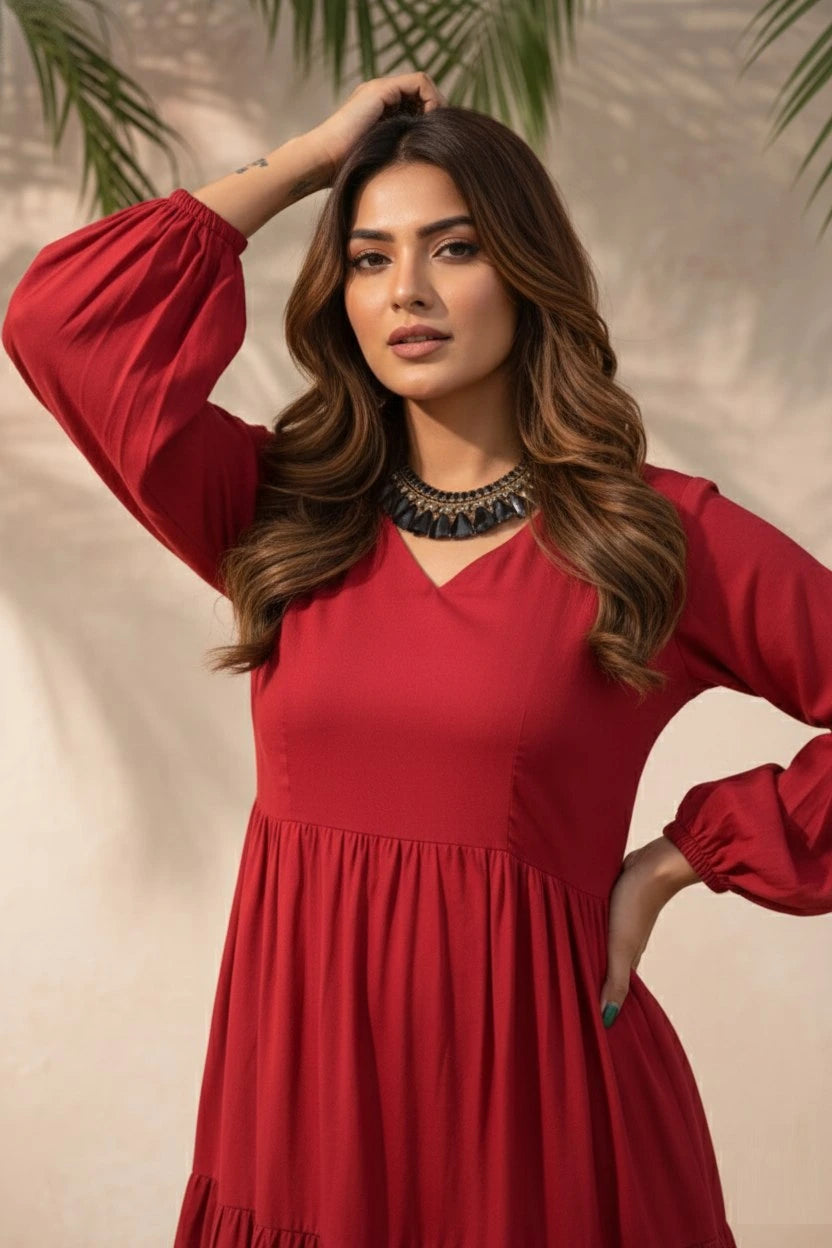 Woman in a red dress posing against a beige background with greenery.