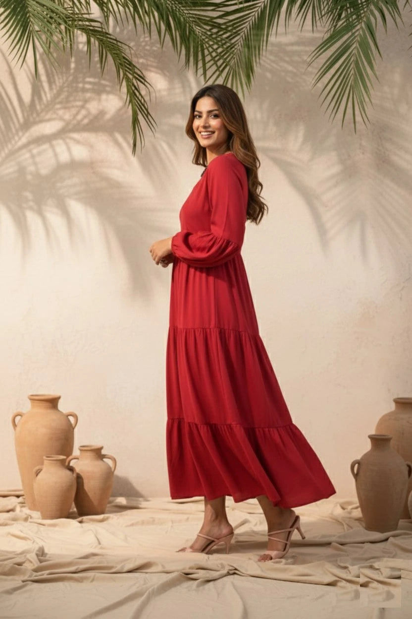 Woman in a red dress standing in front of a neutral wall with decorative vases and palm leaves.