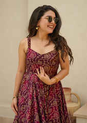 Woman wearing a patterned dress with sunglasses against a beige wall.