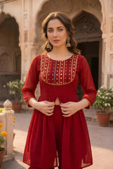 Woman in a red dress with gold detailing standing in front of an architectural background