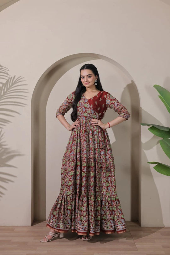Woman wearing a floral dress standing in front of an archway with plants on either side.