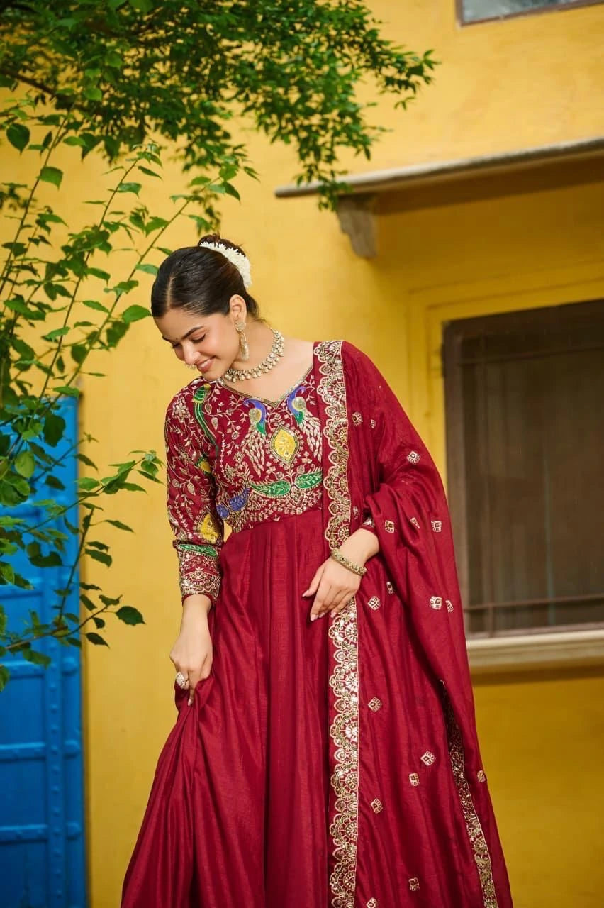 Woman in a red traditional outfit with intricate designs against a yellow wall.