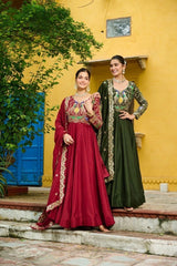 Two women in traditional outfits standing against a yellow wall with a blue door.
