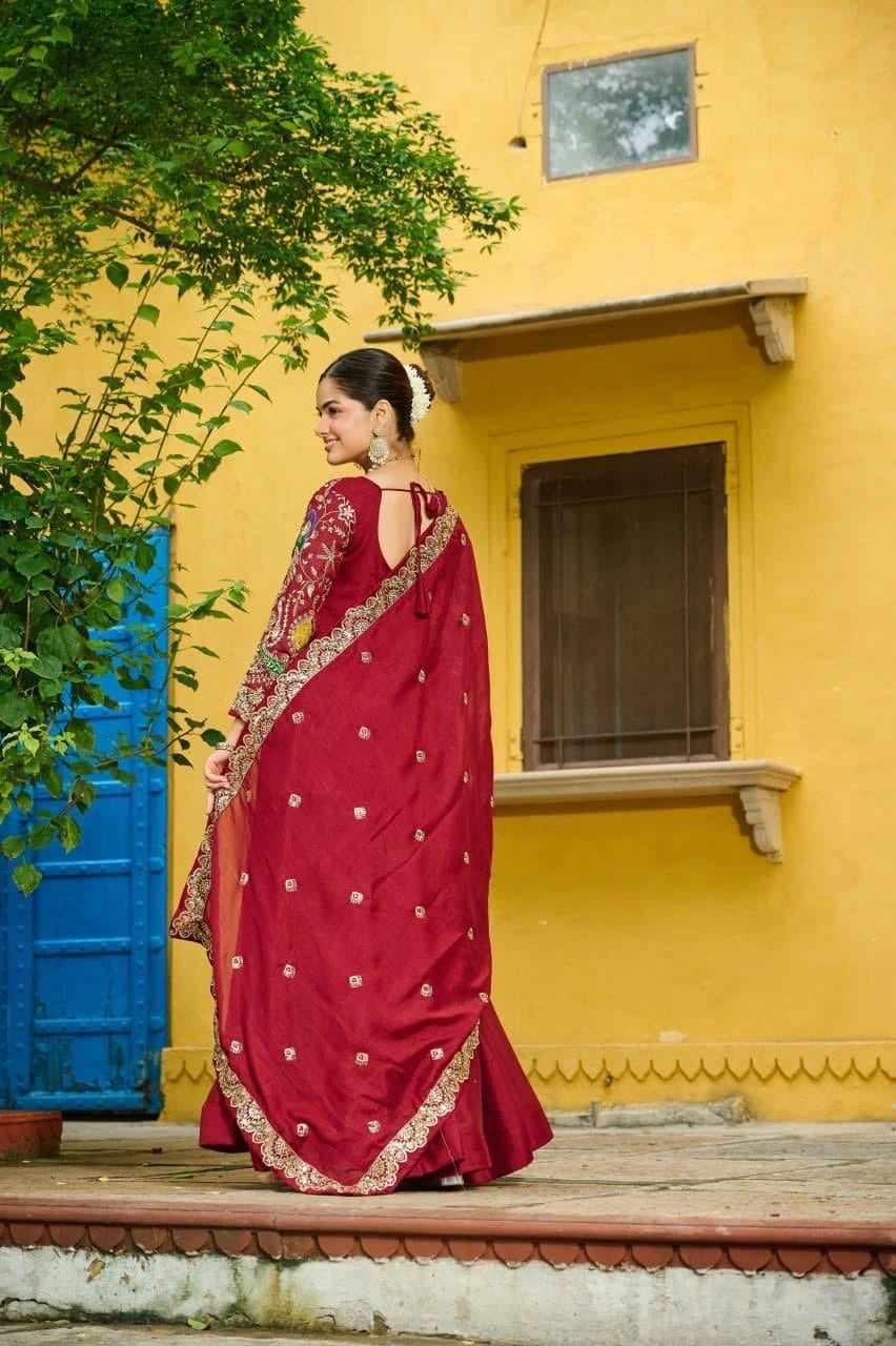 Woman in a red saree standing in front of a yellow wall with a blue door.