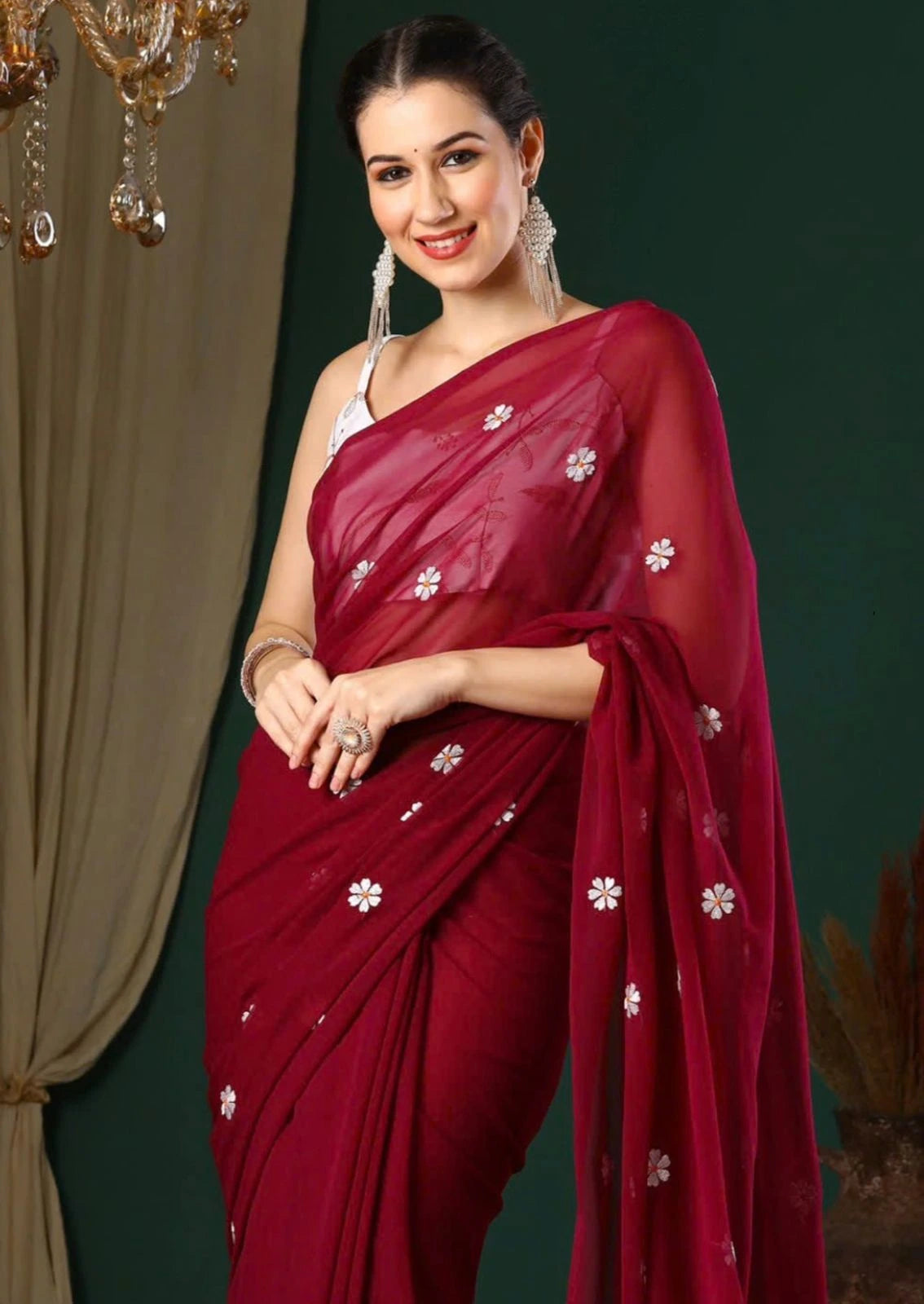 Woman wearing a red saree with white patterns against a dark background